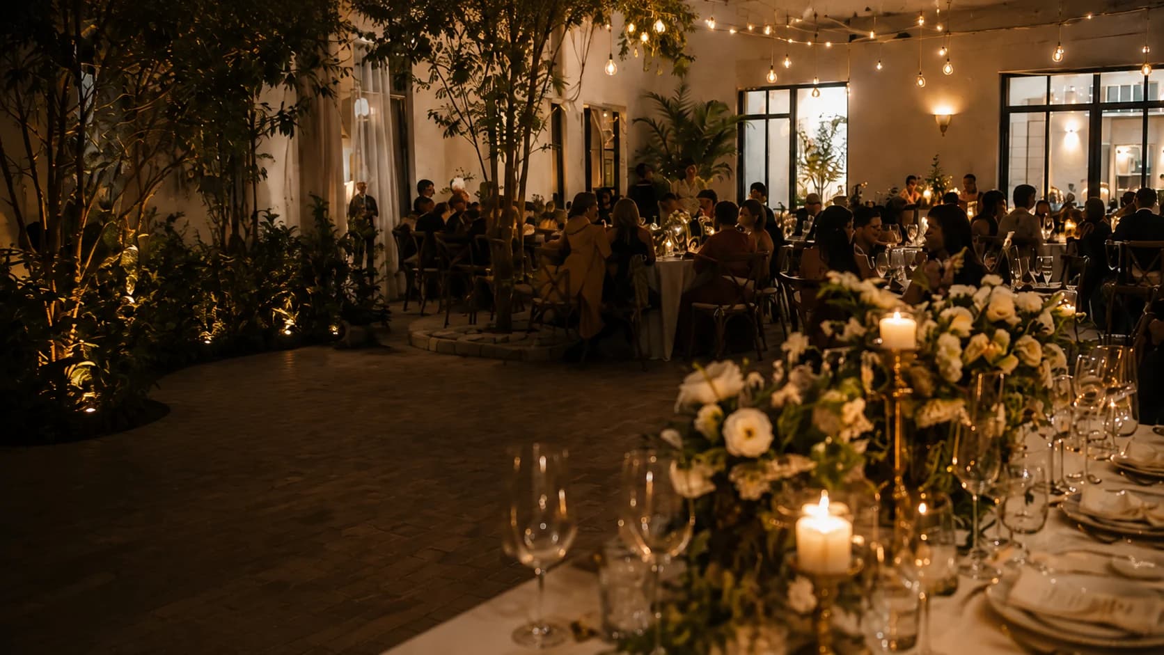 Imagen referencial de una recepción con mesas vestidas, flores blancas y luz cálida